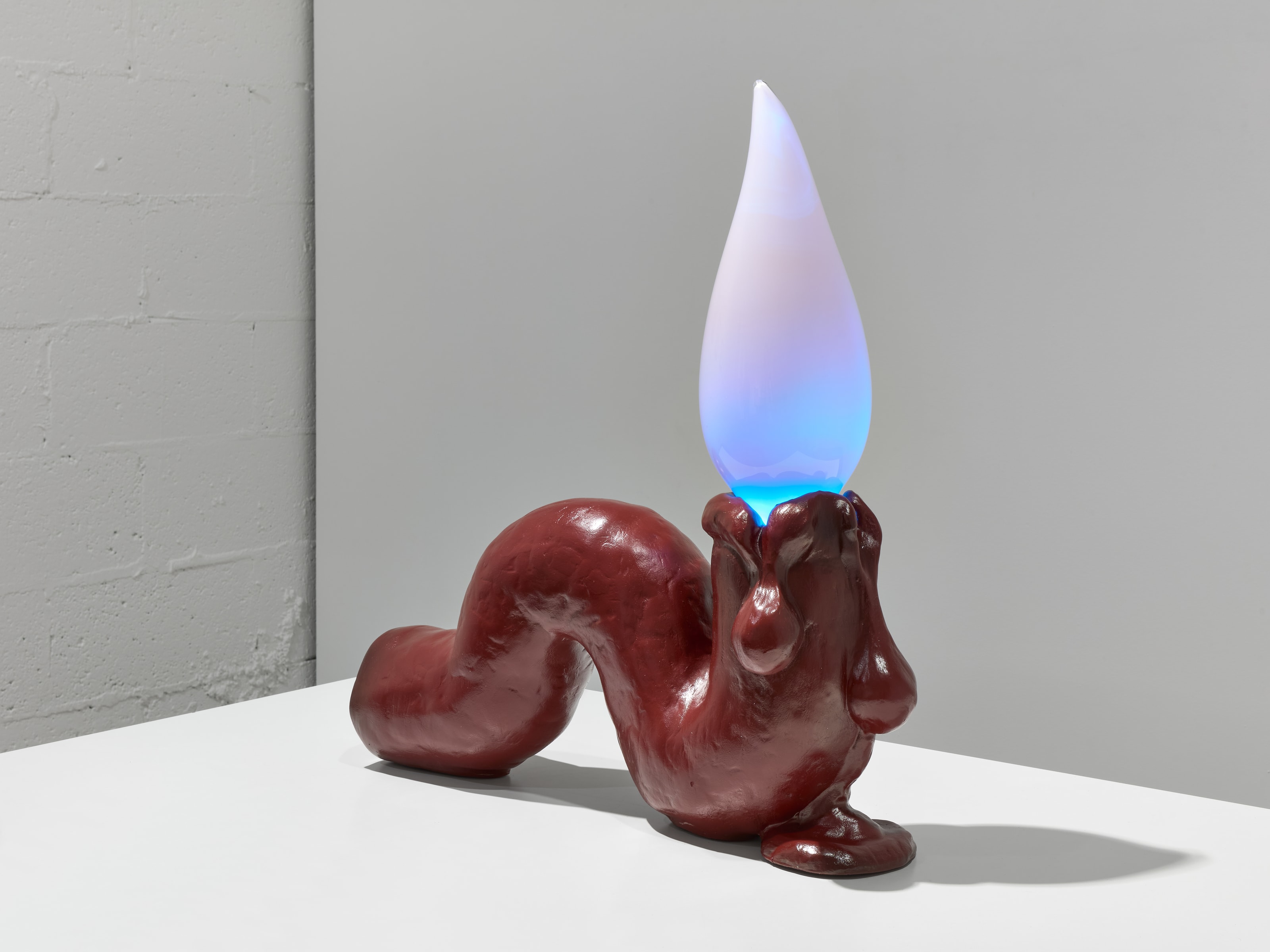 Tai Shani sculpture with a glowing blue flame above a deep red organic form